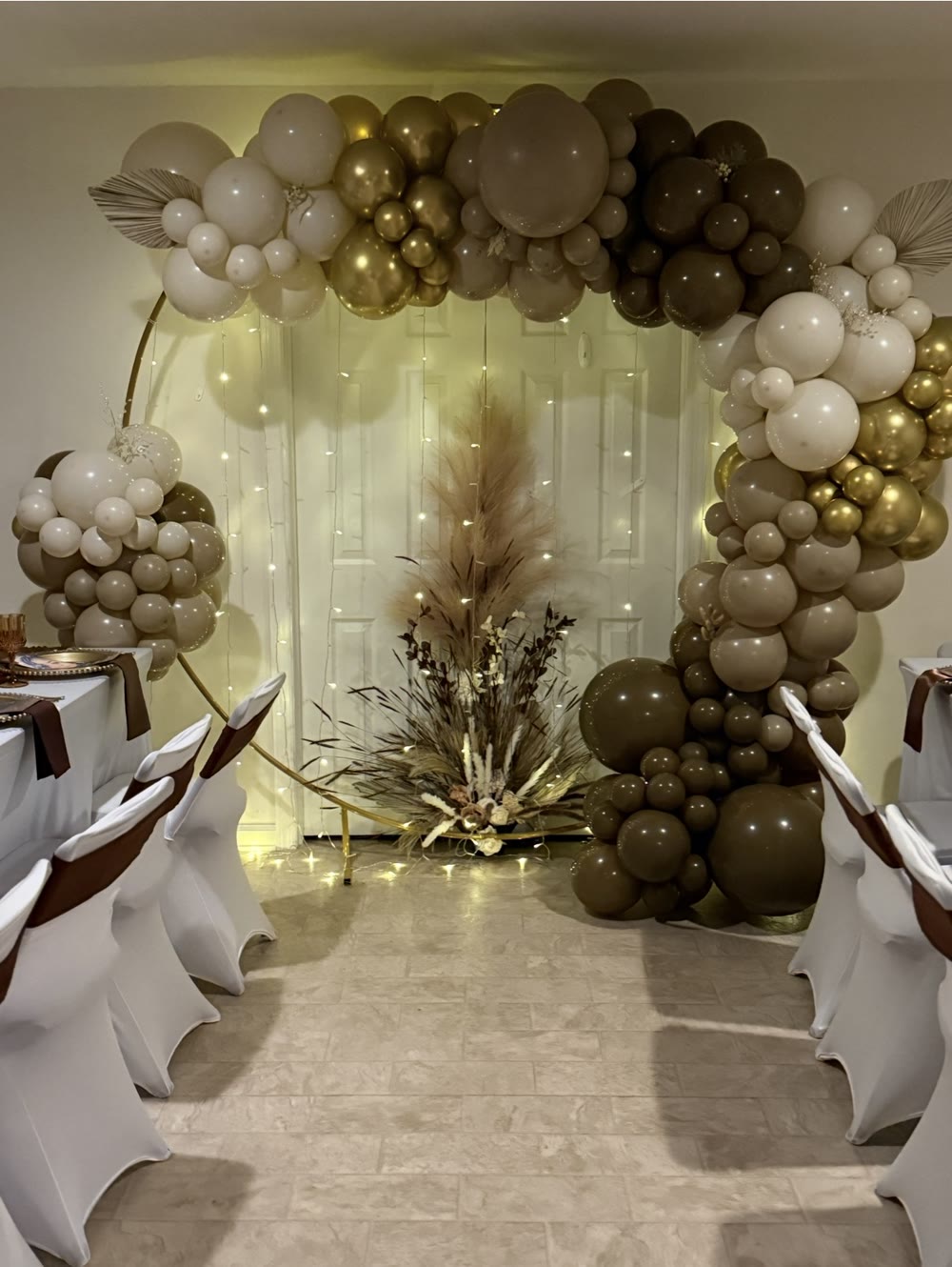 Ivory, taupe, chocolate, and gold organic balloon arch surrounding a circular event backdrop