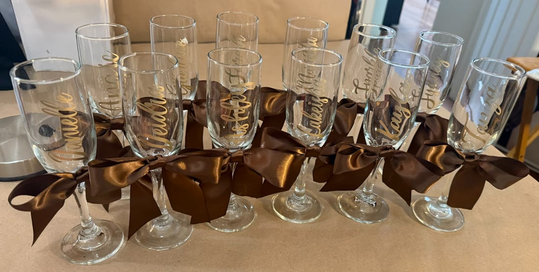 Personalized champagne flutes with gold names and chocolate-brown ribbon bows